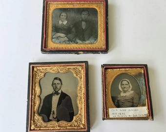 Puede incluir: Tres retratos antiguos enmarcados. Los retratos presentan imágenes en blanco y negro de personas. Los marcos son dorados con diseños ornamentados, y las cajas son negras con ribete rojo. Un retrato tiene el texto "Eliz. Good Johnson 1817-1896".