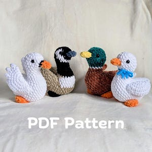 May include: Four handmade crochet duck toys in white, black, brown, and green. Each duck has an orange beak and feet. One duck has a blue bow. The text "PDF Pattern" is displayed below the ducks.