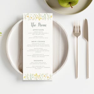 May include: A wedding menu featuring a floral design. The menu includes starters, main course, and desserts. The starters are caprese skewers, shrimp cocktail. The main course is herb-crusted chicken, grilled salmon, and vegetarian risotto. The desserts are vanilla bean creme brulee and mini cheesecake trio.