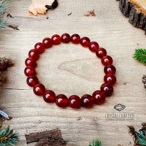 Stunning Carnelian beaded bracelet placed on a wooden background, capturing its fiery orange-red glow and spiritual properties.