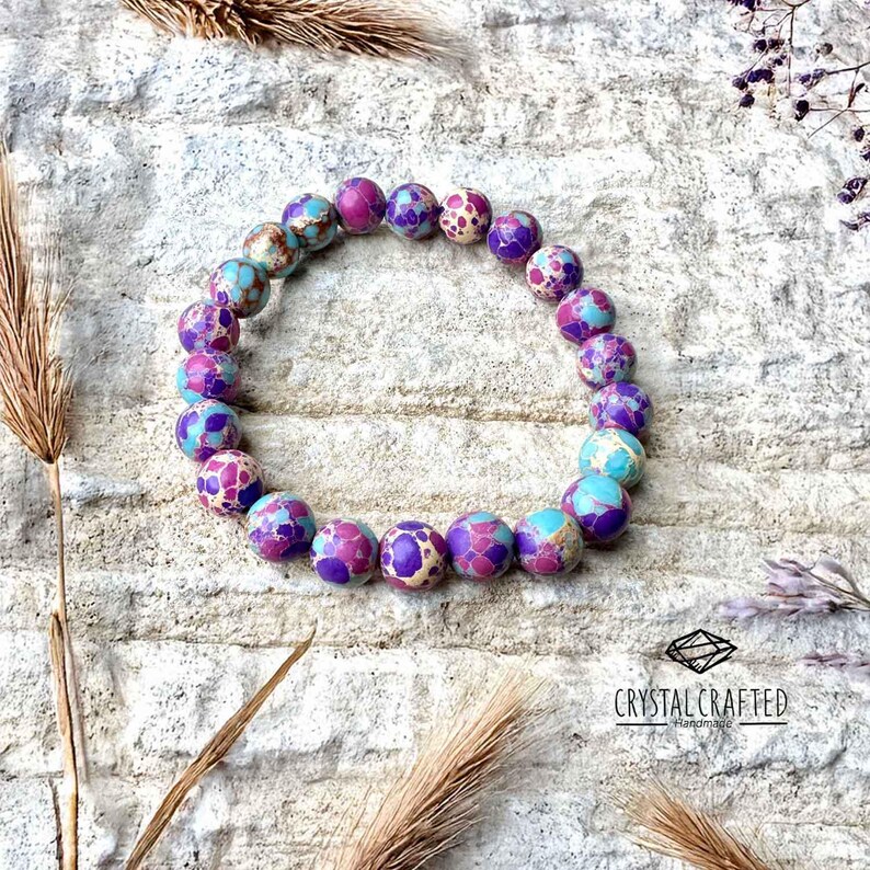 A beautifully crafted stretch bracelet, made of 8mm Sea Sediment Jasper beads, resting on textured stone with soft natural lighting.