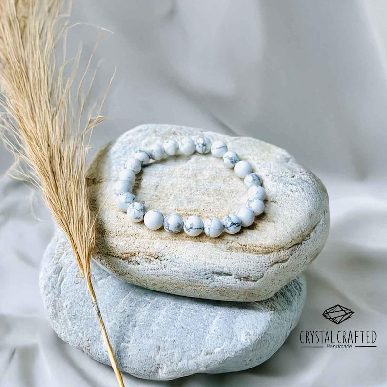 Elegant handmade Howlite bracelet with 8mm white marbled beads, displayed on natural stones. A calming crystal for stress relief and patience