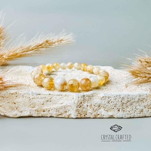 A minimalist, neutral-toned display of the Citrine bracelet on a light stone background, complemented by soft, natural lighting.