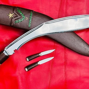 May include: A curved, silver-coloured knife with a brown wooden handle and a leather sheath. The knife has a decorative brass tip and a gold star on the sheath. Two smaller knives with brown wooden handles are also included.