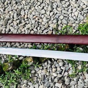 May include: A silver sword with a brown leather scabbard. The sword has a long, sharp blade and a crossguard. The scabbard has a decorative design.