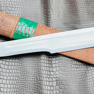 以下が含まれることがあります： 茶色の革製の鞘と緑色の革の巻き付けが施された銀色の剣。鞘には装飾的な模様が施されています。