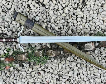 May include: A silver sword with a brown leather scabbard. The sword has a decorative hilt and a sharp blade. The scabbard is decorated with a brown leather strap.