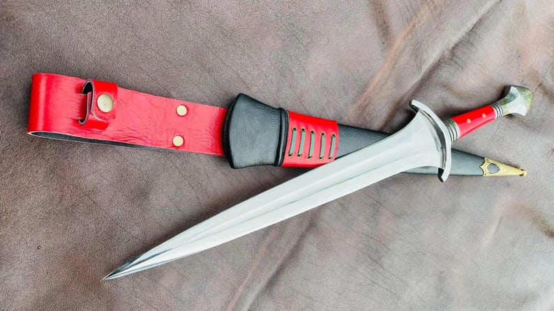 May include: A silver sword with a red and black leather scabbard. The sword has a long, sharp blade and a decorative hilt.