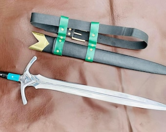 May include: A silver sword with a blue and black handle, and a black sheath with green straps and gold accents. The sword is lying on a brown surface. The sword's blade is long and pointed.