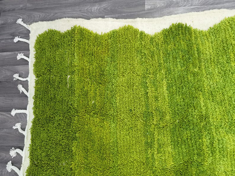 May include: A green shag rug with a white border. The rug has a wavy edge and a textured surface.