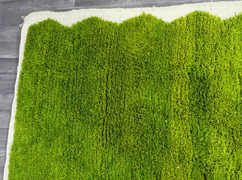 May include: A green shag rug with a white border. The rug has a wavy edge and is made of soft, fluffy fibers.