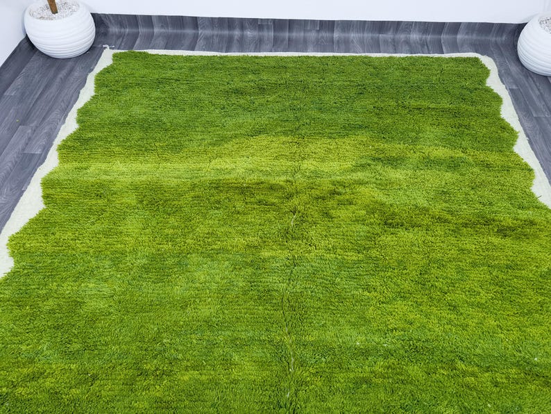 May include: A green shag rug with a white border. The rug has a wavy edge and is made of soft, fluffy fibers.