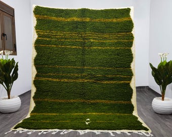 May include: A green and gold striped rug with a white fringe. The rug is made of wool and has a soft, fluffy texture.