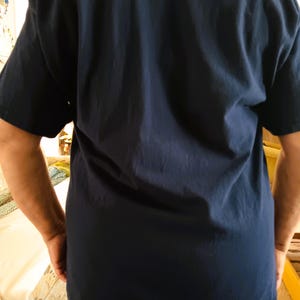 May include: Navy blue short-sleeve t-shirt. The shirt is made of a soft, comfortable material. The back of the shirt is visible, with the sleeves and the bottom hem of the shirt in view.