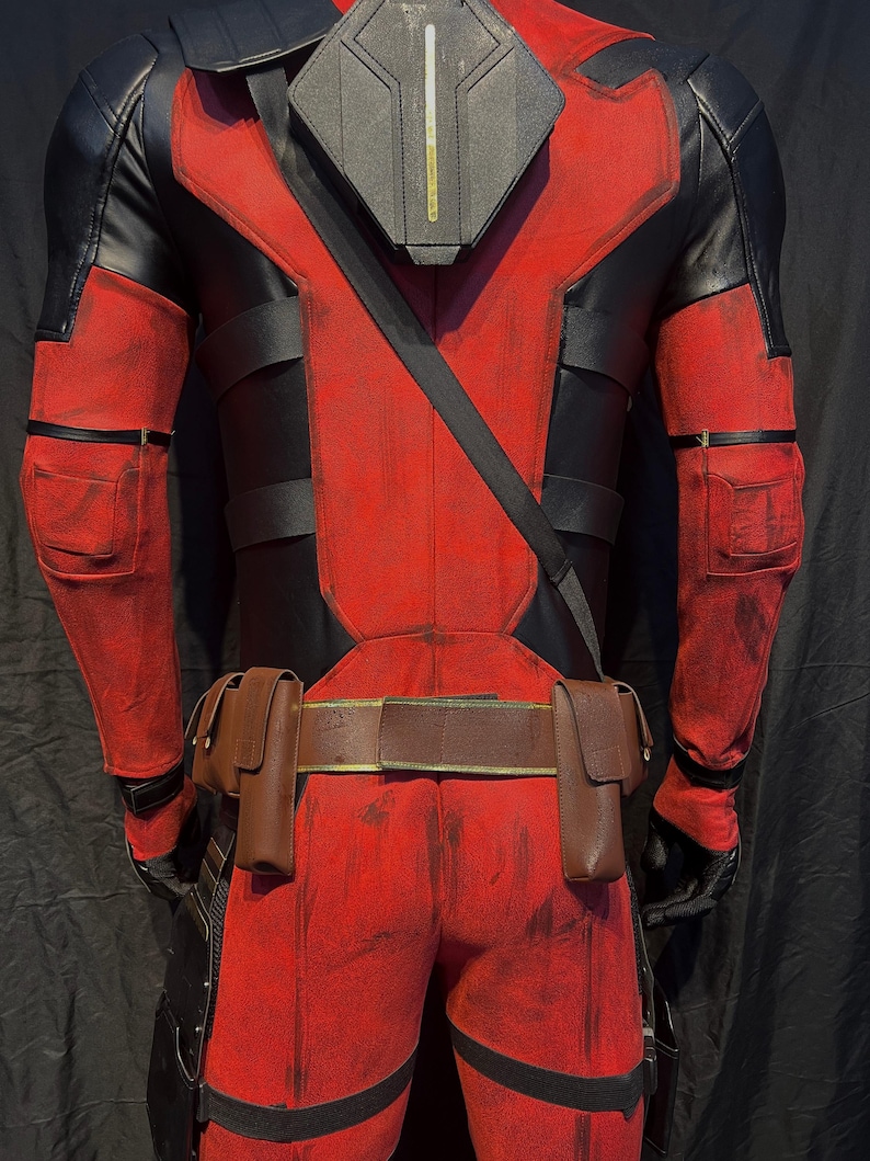 Puede incluir: Un traje de superh&eacute;roe rojo y negro con un cintur&oacute;n negro y bolsas. El traje tiene un aspecto desgastado con pintura roja y negra descolorida.