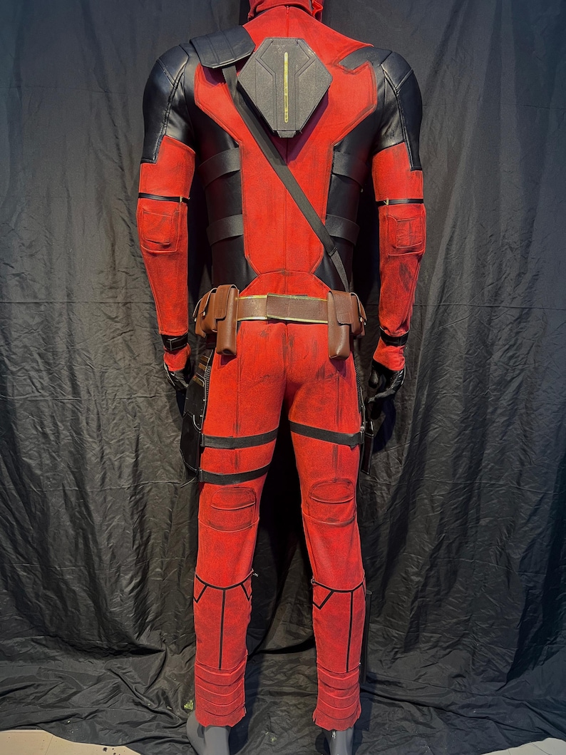 Puede incluir: Un disfraz de Deadpool rojo y negro con un cintur&oacute;n negro y bolsas. El disfraz tiene un aspecto desgastado con acentos rojos y negros descoloridos.