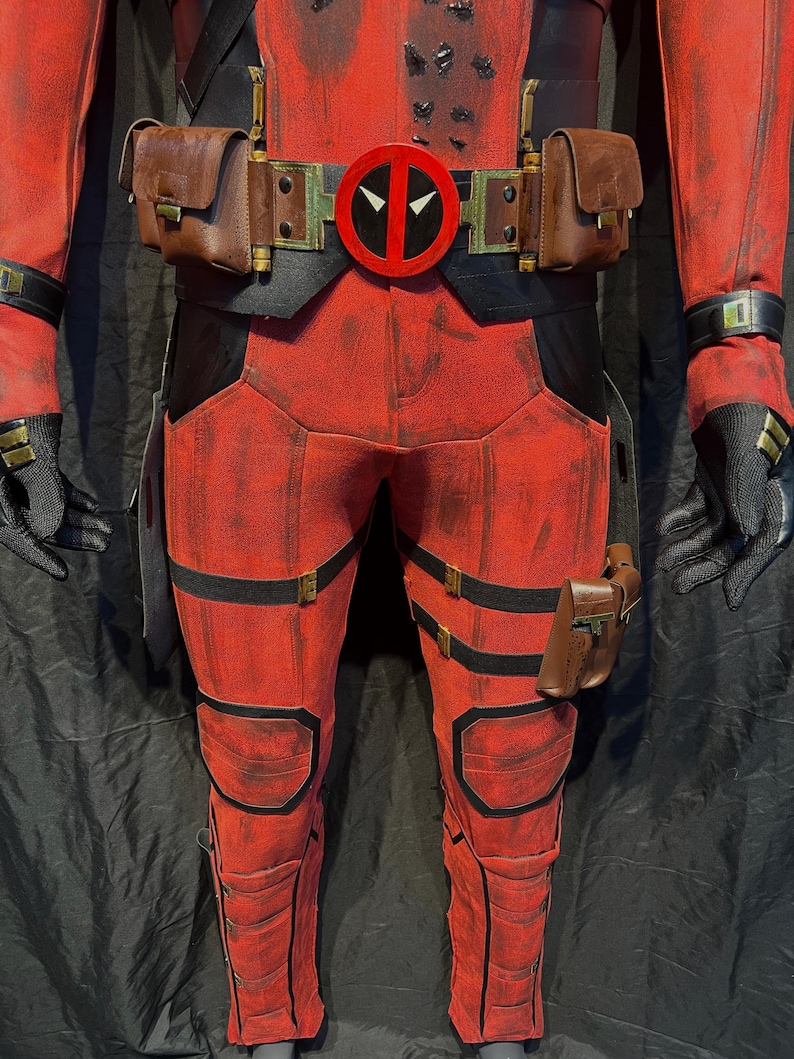 Puede incluir: Traje rojo y negro con un cintur&oacute;n con un logotipo de Deadpool rojo. El traje tiene m&uacute;ltiples correas y bolsas.