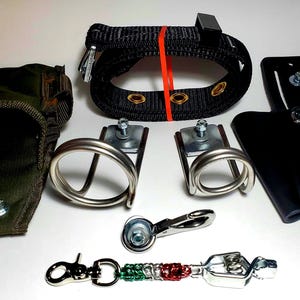 May include: A set of black leather tool belts with a variety of metal hardware, including a black nylon belt with a red rubber band, a green canvas pouch, two metal rings, a metal hook, and a metal chain with green, red, and white beads.