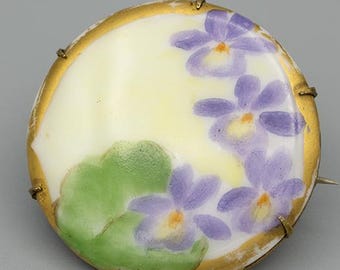 Antique 1900s Victorian hand-painted floral porcelain brooch with purple flowers, green leaves, a gold border and brass backing