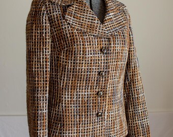 May include: A vintage blazer in a brown, black, and white checkered pattern. The jacket has a notched collar, three buttons, and long sleeves. The blazer is displayed on a mannequin.