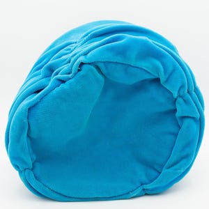 Puede incluir: Un sombrero de terciopelo turquesa brillante, visto desde el interior. El sombrero tiene un dise&ntilde;o fruncido en la parte superior y una textura suave y afelpada. El sombrero es de color liso y parece estar hecho de una tela suave.