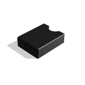 Puede incluir: Un tarjetero negro liso con un recorte curvo en un lado. El soporte rectangular está hecho de un material liso y brillante y proyecta una sombra sobre un fondo blanco.