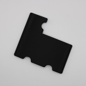 Puede incluir: Un porta tarjetas de plástico negro con dos recortes en los bordes superior e inferior.