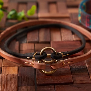 May include: Two leather bracelets with a gold-toned metal ring connector. The bracelets are brown and black and are layered on top of each other.