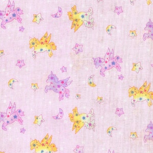 May include: A pink fabric with a repeating pattern of yellow, pink and purple unicorns with wings and stars. The unicorns are flying and have a whimsical look.