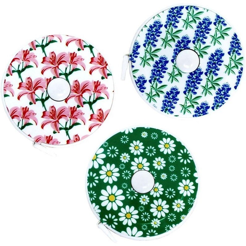 Pode incluir: Tr&ecirc;s fitas m&eacute;tricas retr&aacute;teis com diferentes padr&otilde;es florais. A primeira fita m&eacute;trica tem um padr&atilde;o floral rosa e branco com l&iacute;rios vermelhos. A segunda fita m&eacute;trica tem um padr&atilde;o floral azul e branco com lupinos azuis. A terceira fita m&eacute;trica tem um padr&atilde;o floral verde e branco com margaridas brancas.