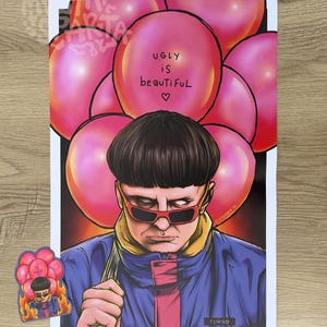 May include: A rectangular art print and a matching sticker featuring a person with a bowl cut hairstyle, wearing red-rimmed sunglasses and a blue and pink jacket. The person is surrounded by pink balloons, one with the text UGLY iS beAuTiFuL.