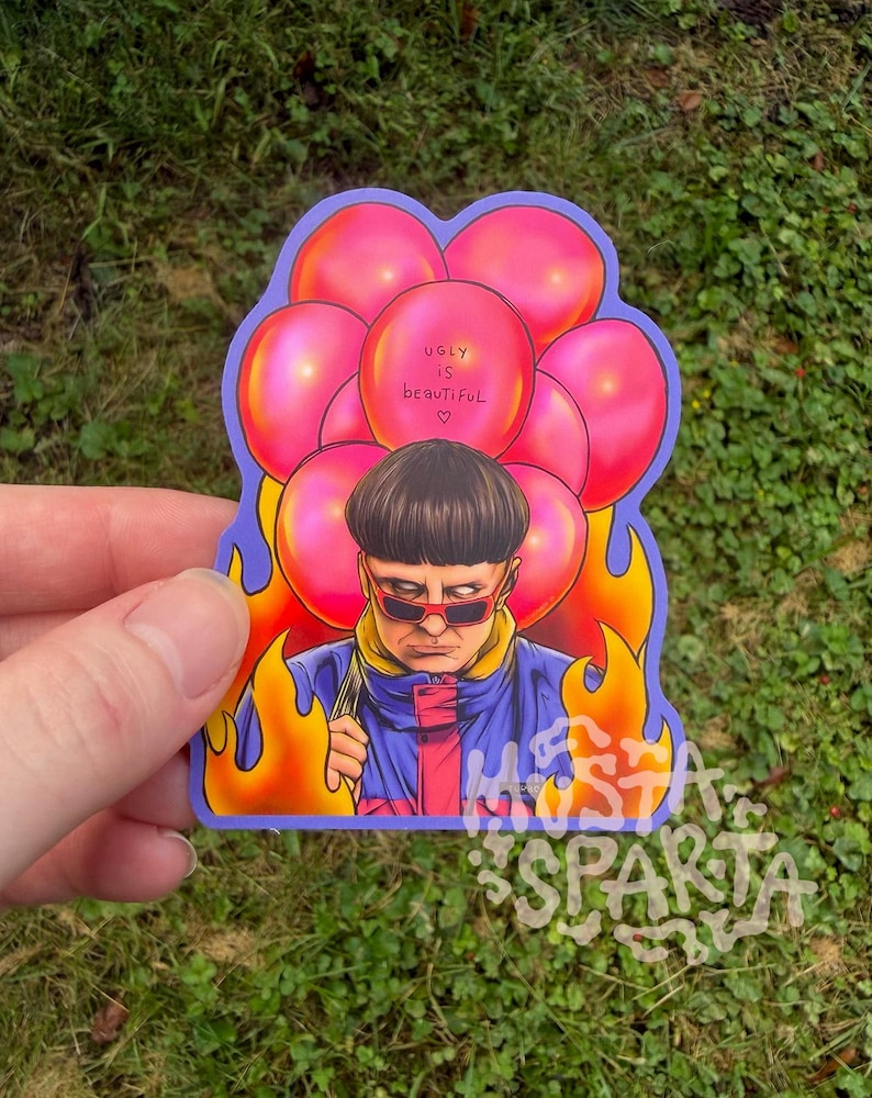 May include: A die-cut sticker featuring a person with a bowl cut wearing red-tinted sunglasses and a blue and yellow jacket. The person is surrounded by bright pink balloons and orange flames. One balloon has the text "ugly is beautiful" written on it.