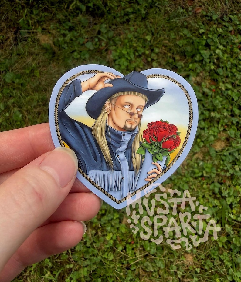 May include: A heart-shaped sticker featuring an illustration of a person with long blonde hair, a mullet, and a goatee, wearing a dark blue cowboy hat and a matching jacket with fringe. The person holds a bouquet of red roses against a yellow sky.
