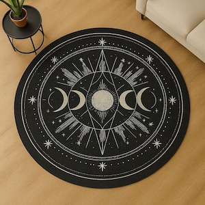 Pode incluir: Tapete redondo preto com um design celestial. O tapete apresenta um design central de raios de sol, três luas crescentes e inúmeras estrelas. Uma borda pontilhada envolve o design central. O tapete está colocado sobre um chão de madeira.