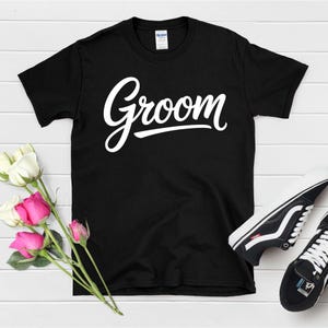 Peut inclure: T-shirt noir avec le mot "Groom" en lettres blanches en cursive.