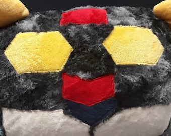 May include: A plush toy shaped like a bee with black, yellow, red, and blue fabric. The bee has large yellow ears and a black and yellow striped body.