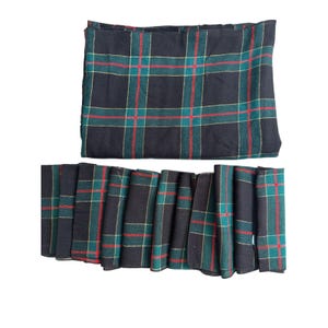 May include: A set of fabric napkins and a matching tablecloth featuring a dark navy blue base with a grid pattern of thin green and red lines. The textile items are folded and arranged to display the consistent plaid design throughout.