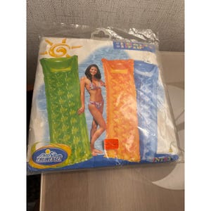 May include: A clear plastic package containing three inflatable pool floats in green, orange, and blue. The packaging features a graphic of a person in a bikini and the text The Wet Set. Dimensions of 188 cm x 71 cm or 74 inches x 28 inches are printed.