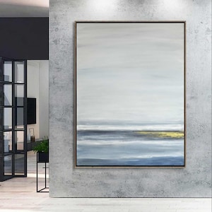 Könnte beinhalten: Abstrakte Landschaftsmalerei mit minimalistischem Design. Das Kunstwerk zeigt horizontale Bänder in Blau, Grau und Weiß, mit einem Hauch von Gold am unteren Rand. Das Gemälde ist in einem einfachen, dunklen Holzrahmen gerahmt.