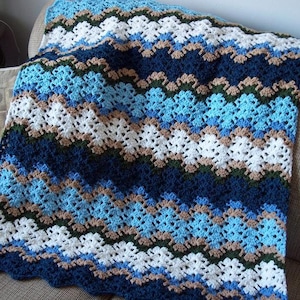 May include: A crocheted blanket with a wavy pattern in shades of blue, white, brown, and green.