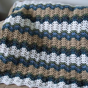 May include: A crocheted blanket with a chevron pattern in shades of white, tan, green, and blue.