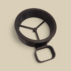 Pode incluir: Um anel de plástico preto com um divisor de três pontas no interior. O anel tem uma alça lateral.