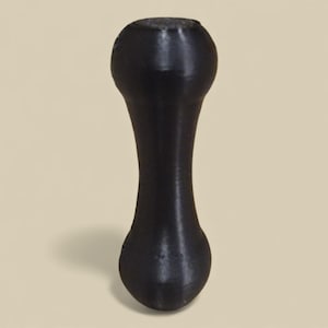 May include: A black, hourglass-shaped object with rounded ends and a narrow centre. The object has a smooth, matte finish and casts a shadow on a neutral background. It appears to be a decorative or functional item.
