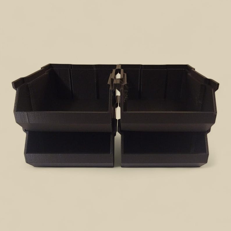 K&ouml;nnte beinhalten: Zwei dunkelbraune Kunststoff-Aufbewahrungsboxen, die durch ein zentrales Scharnier verbunden sind. Jede Box hat eine rechteckige Form mit einem unteren Regal und einer leicht abgewinkelten Oberkante. Die Boxen sind f&uuml;r die Organisation kleiner Gegenst&auml;nde konzipiert.