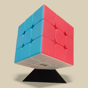 May include: A colorful Rubik's Cube with blue, red, and white sides, displayed on a black stand. The cube is a classic puzzle toy, perfect for problem-solving and entertainment. The cube is a 3x3 cube.
