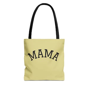May include: A light yellow tote bag with black handles. The word "MAMA" is printed in large, black, arched letters across the front of the bag. The bag is designed for carrying items.