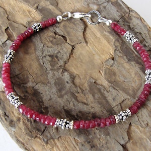 May include: A red gemstone bracelet with silver beads and a lobster clasp closure.