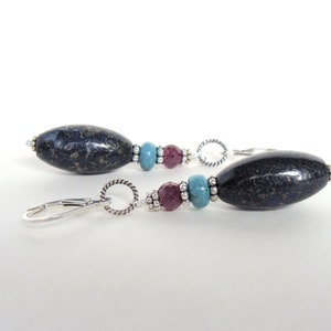 May include: A pair of dangle earrings with a dark blue oval-shaped stone, turquoise beads, and pink beads. The earrings have silver hooks and silver bead accents.