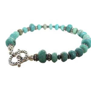 May include: A turquoise gemstone bracelet with a silver toggle clasp. The bracelet features faceted turquoise beads and silver spacer beads.