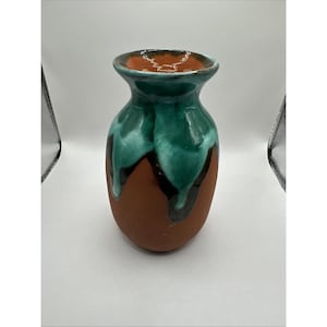 Könnte beinhalten: Eine handgefertigte Keramikvase mit rundem Boden und ausgestelltem Oberteil. Die Vase hat einen satten, erdig-braunen Sockel mit einer leuchtenden türkisfarbenen Glasur, die an den Seiten herunterläuft. Der Rand ist warm, rötlich-braun.